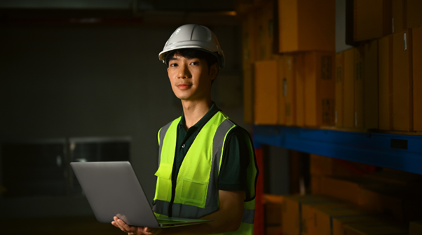 Logistics operator photo of a logistics worker in a safety vest with a laptop.